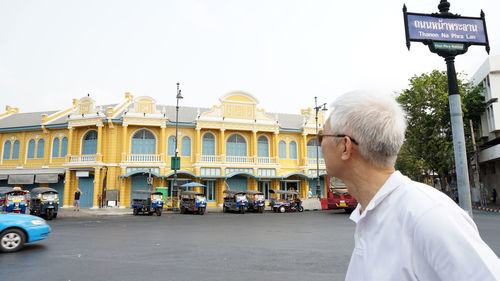 Man on street in city against sky