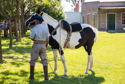 Full length of men standing on field with his horse