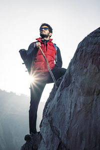 Young traveler in red snow jacket and a backpack standing on blue isolated background. 