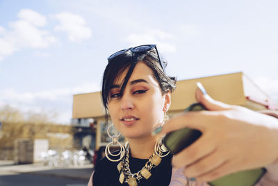 Young woman taking selfie with smart phone in city