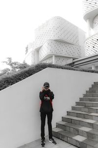 Full length of man standing on railing against building