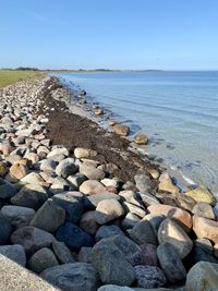 Stones on beach against clear sky