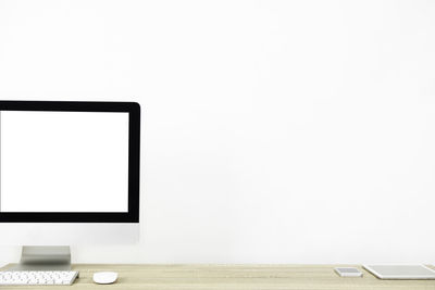 Low angle view of laptop on table against white wall