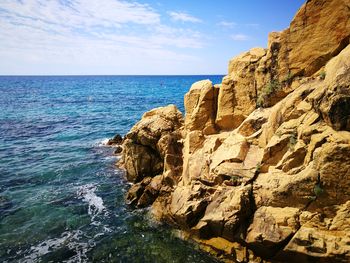 Rock formations by sea against sky