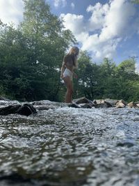 Full length of woman standing on rock against sky