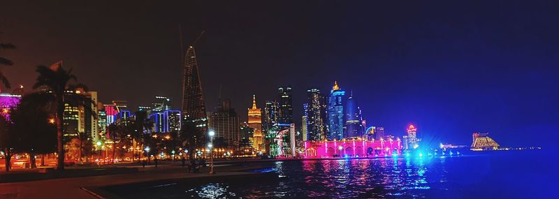 Illuminated buildings in city against sky at night