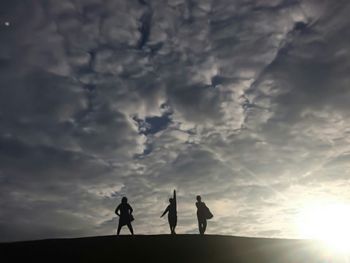 Silhouette people standing against sky during sunset