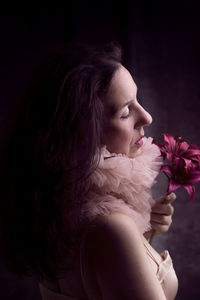 Close-up of woman holding flower against black background