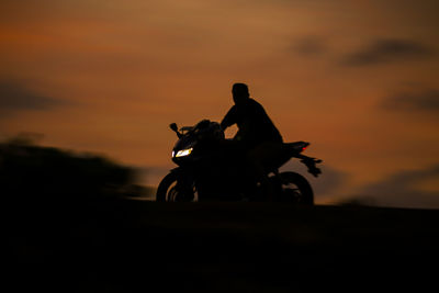 Silhouette people riding motorcycle against sky during sunset