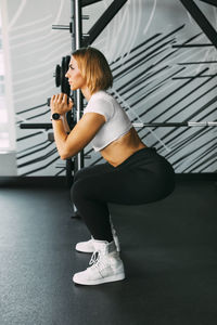 A sporty girl performs squats with dumbbells during a workout in the gym. sports, fitness