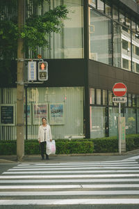 People crossing road sign against building