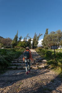 Rear view of woman walking on field against clear sky
