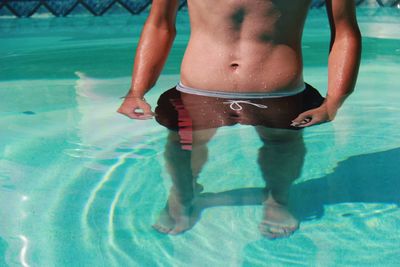 Low section of shirtless man in swimming pool