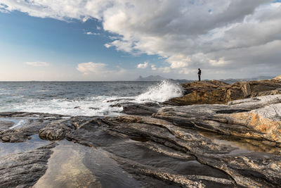 Rocky shore against cloudy sky