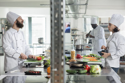 Chef talking with colleague in restaurant kitchen while preparing food