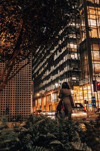Rear view of woman sitting on illuminated building at night