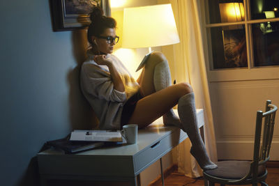 Side view of young woman sitting at home