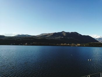 Scenic view of lake and mountains against clear blue sky