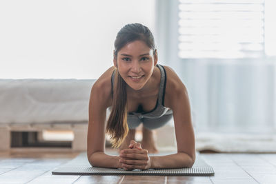 Portrait of smiling young woman exercising at home