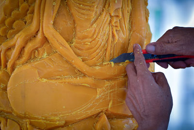 Cropped hands carving wax