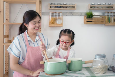 Girl with mother preparing food in kitchen at home