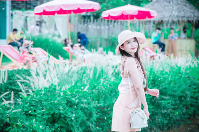 Portrait of young woman standing against plants