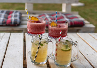 Close-up of cocktails in vintage glasses and jars on white pallet table in bar