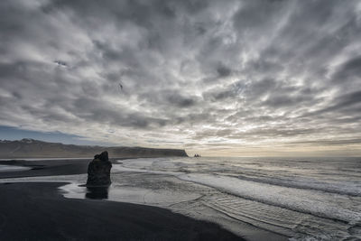 Rear view of woman standing on beach against sky