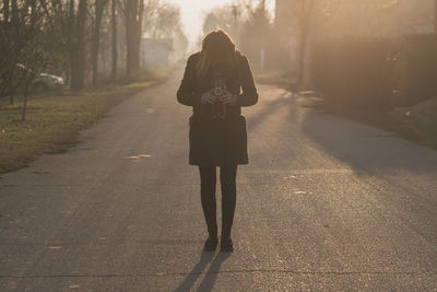 Young woman photographing through camera on road