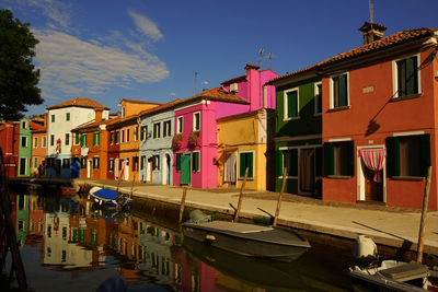 Boats moored in canal by buildings against sky in city