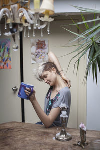 Young woman holding mug while sitting indoors