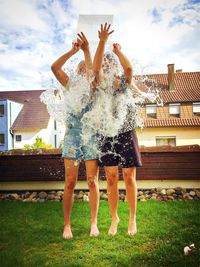 Female friends pouring water on themselves at yard