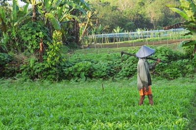 Side view of man with work tool walking on field