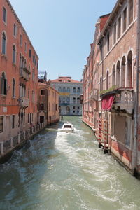 Canal amidst buildings in city against clear sky