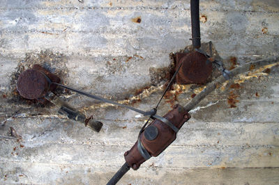 Close-up of rusty metal against wall under bridge