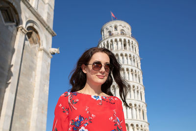 Smiling woman standing against leaning tower of pisa in italy