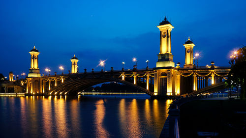 Illuminated bridge over river at night