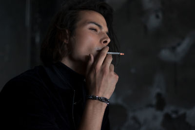 Young man smoking cigarette at home