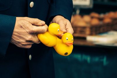 Midsection of man holding yellow rubber ducks