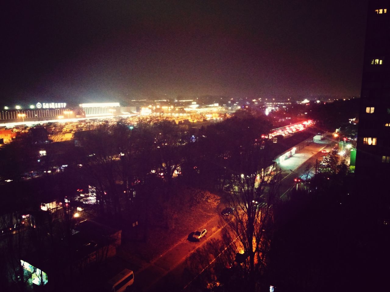 illuminated, night, city, building exterior, architecture, built structure, cityscape, high angle view, city life, street, city street, street light, traffic, road, crowded, lighting equipment, residential district, sky, car, light - natural phenomenon