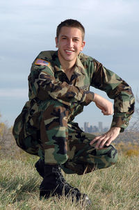 Young north american soldier in uniform, poses on a on hilltop