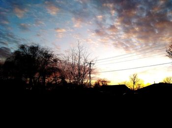 Silhouette trees on field against sky at sunset