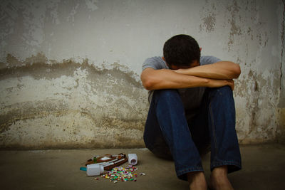 Tired man sitting against wall