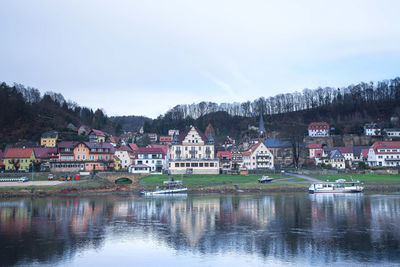 Houses by lake against sky in city