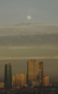 Modern cityscape against sky during sunset