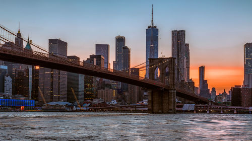 Bridge over river by buildings against sky in city