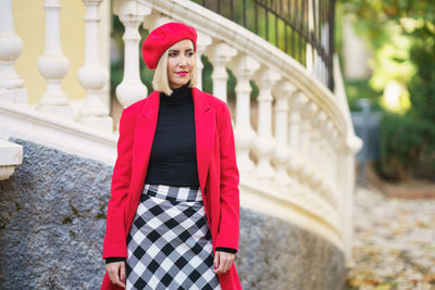 Portrait of young woman standing against building