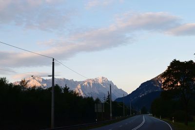 Road by mountains against sky