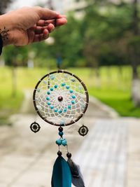 Close-up of hand holding dreamcatcher outdoors