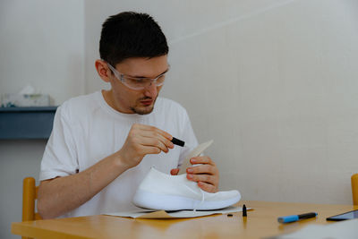 A young man repairs shoes at home.